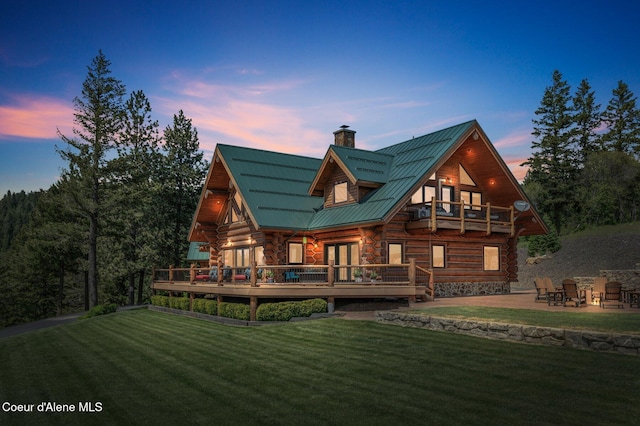 17442 S Painted Rose Rd, Worley, ID 83876 - back of house at dusk featuring a balcony, a lawn, log exterior, and metal roof