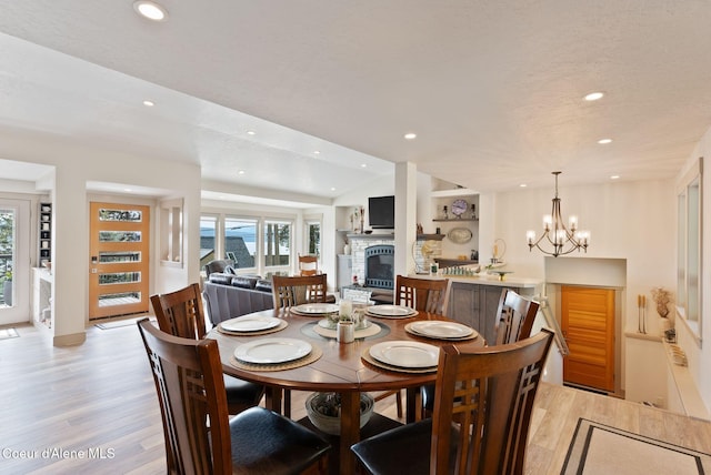 2406 S Silver Beach Rd, Coeur Dalene, ID 83814 - dining room featuring light wood-style flooring, a fireplace with raised hearth, recessed lighting, vaulted ceiling, and a chandelier