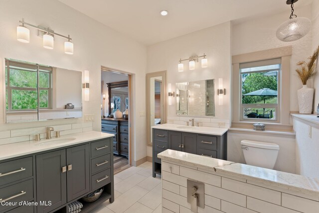 2406 S Silver Beach Rd, Coeur Dalene, ID 83814 - full bathroom featuring two vanities, toilet, tile patterned floors, and decorative backsplash