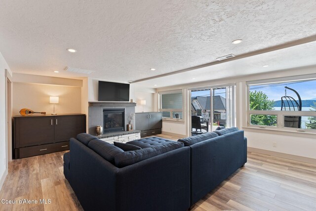 2406 S Silver Beach Rd, Coeur Dalene, ID 83814 - living area featuring light wood-style flooring, a glass covered fireplace, recessed lighting, a textured ceiling, and baseboards