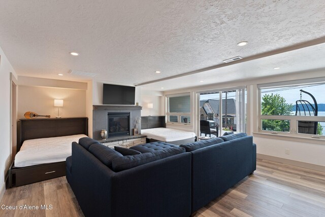 2406 S Silver Beach Rd, Coeur Dalene, ID 83814 - living area with wood finished floors, a glass covered fireplace, baseboards, recessed lighting, and a textured ceiling