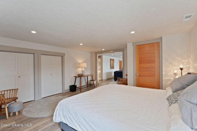 2406 S Silver Beach Rd, Coeur Dalene, ID 83814 - bedroom featuring wood finished floors, recessed lighting, two closets, and ensuite bath