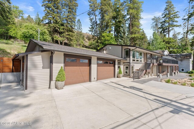 2406 S Silver Beach Rd, Coeur Dalene, ID 83814 - view of front of home with stairway, a garage, concrete driveway, an outbuilding, and a wooden deck