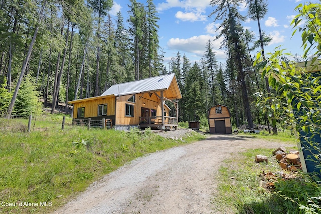 99 Broten Way, Sagle, ID 83860 - view of front of property featuring dirt driveway, an outbuilding, metal roof, a wooded view, and board and batten siding