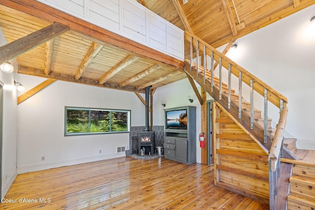 99 Broten Way, Sagle, ID 83860 - unfurnished living room with wooden ceiling with exposed beams, stairway, a wood stove, hardwood / wood-style flooring, and baseboards
