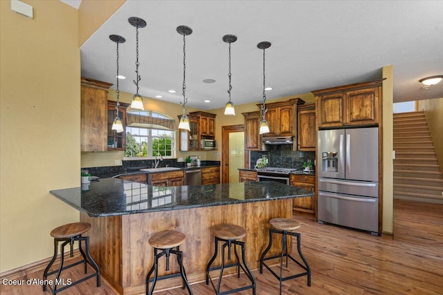 1874 W Polo Green Ave, Post Falls, ID 83854 - kitchen featuring stainless steel appliances, a peninsula, a sink, backsplash, and hanging light fixtures