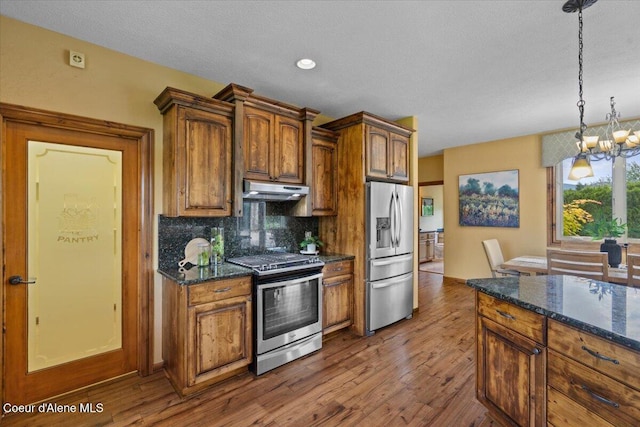 1874 W Polo Green Ave, Post Falls, ID 83854 - kitchen featuring appliances with stainless steel finishes, under cabinet range hood, a chandelier, backsplash, and decorative light fixtures