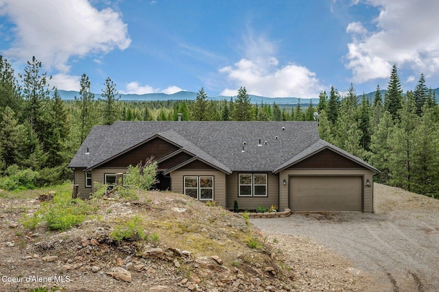 27968 N Timber Ridge Rd, Rathdrum, ID 83858 - view of front of home featuring a mountain view, an attached garage, dirt driveway, a shingled roof, and a wooded view