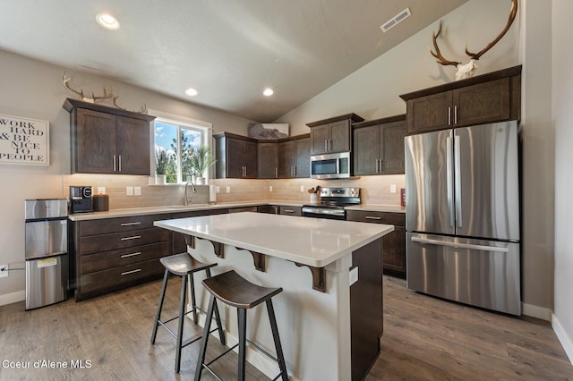 27968 N Timber Ridge Rd, Rathdrum, ID 83858 - kitchen featuring stainless steel appliances, a sink, dark brown cabinets, tasteful backsplash, and vaulted ceiling