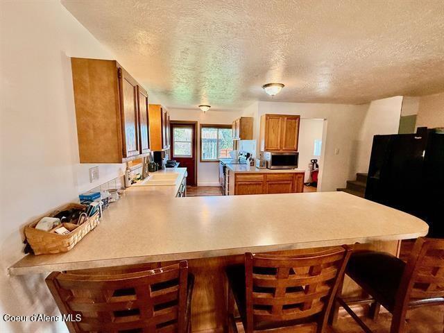 602 Spalding Ave, Winchester, ID 83555 - kitchen with stainless steel appliances, brown cabinets, a peninsula, a textured ceiling, and light countertops