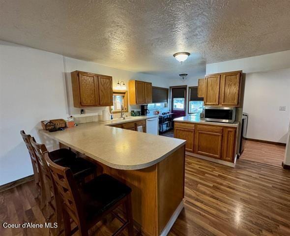602 Spalding Ave, Winchester, ID 83555 - kitchen featuring stainless steel microwave, brown cabinetry, a peninsula, a textured ceiling, and light countertops
