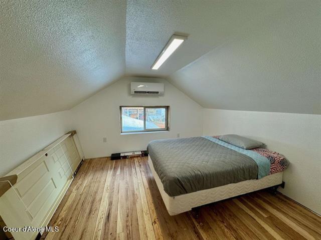 602 Spalding Ave, Winchester, ID 83555 - bedroom featuring a wall mounted air conditioner, a textured ceiling, hardwood / wood-style floors, and lofted ceiling