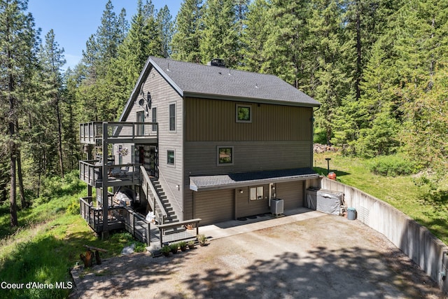 5005 W Cougar Estates Rd, Coeur Dalene, ID 83814 - view of front of house with a deck, driveway, roof with shingles, stairs, and a view of trees