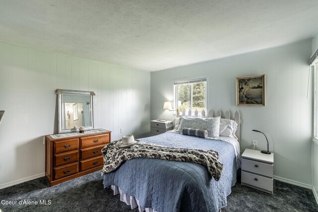 13744 N Hauser Lake Rd, Hauser, ID 83854 - bedroom with dark carpet, baseboards, and a textured ceiling