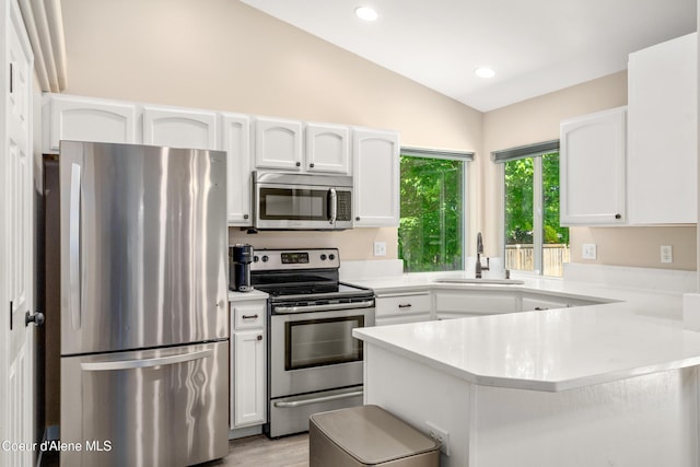 1800 N Willamette Dr, Post Falls, ID 83854 - kitchen featuring stainless steel appliances, vaulted ceiling, a sink, white cabinets, and light countertops