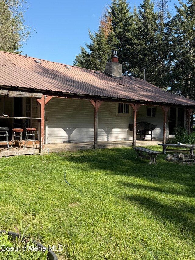 30625 Pastime St, Athol, ID 83801 - view of side of property featuring metal roof, a chimney, a yard, and a patio