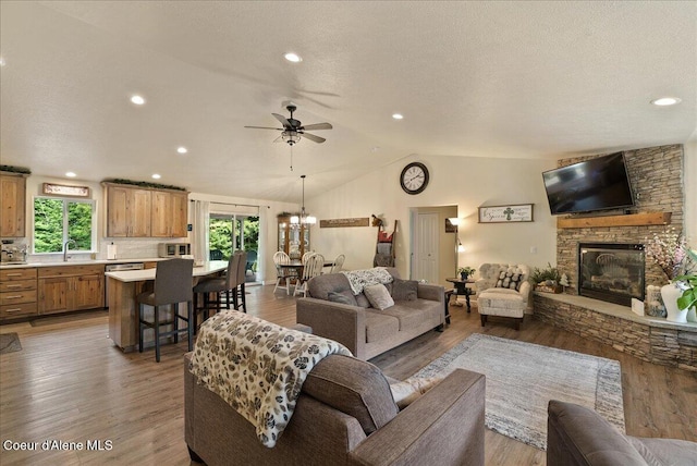 12671 E Trout Pond Rd, Athol, ID 83801 - living room with vaulted ceiling, a stone fireplace, light wood finished floors, ceiling fan, and a textured ceiling