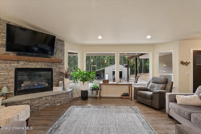 12671 E Trout Pond Rd, Athol, ID 83801 - living room featuring wood finished floors, a textured ceiling, a stone fireplace, and recessed lighting