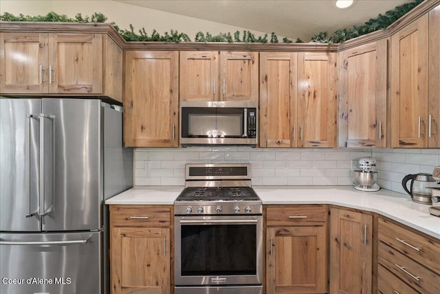 12671 E Trout Pond Rd, Athol, ID 83801 - kitchen featuring appliances with stainless steel finishes, tasteful backsplash, light countertops, brown cabinets, and lofted ceiling