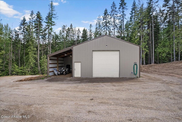 12671 E Trout Pond Rd, Athol, ID 83801 - garage with a garage, driveway, and a view of trees