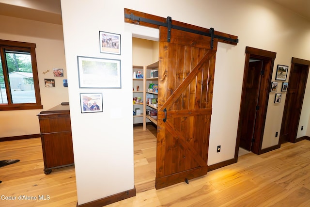 9057 W Benton Way, Coeur Dalene, ID 83814 - corridor with light wood-style floors, a barn door, and baseboards