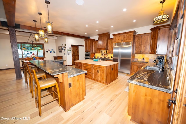 9057 W Benton Way, Coeur Dalene, ID 83814 - kitchen featuring built in refrigerator, a spacious island, a sink, brown cabinetry, and light wood finished floors