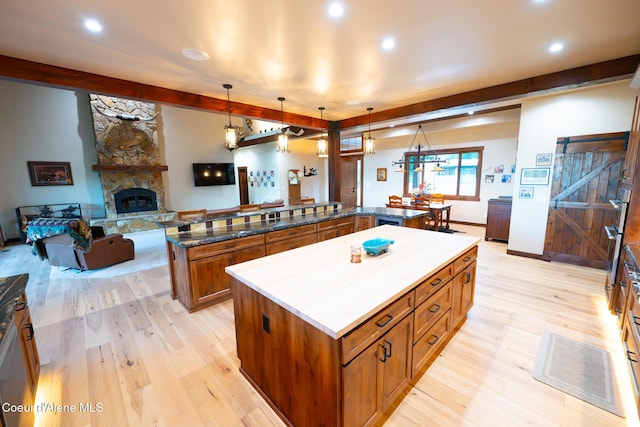 9057 W Benton Way, Coeur Dalene, ID 83814 - kitchen featuring a large island, brown cabinets, light wood-style flooring, open floor plan, and beamed ceiling