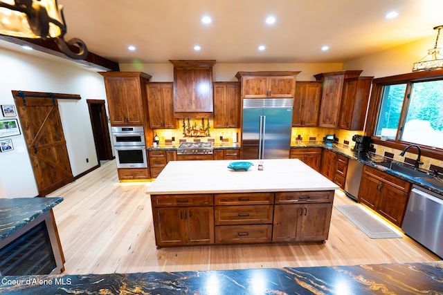 9057 W Benton Way, Coeur Dalene, ID 83814 - kitchen featuring appliances with stainless steel finishes, a sink, light wood-style floors, a barn door, and recessed lighting
