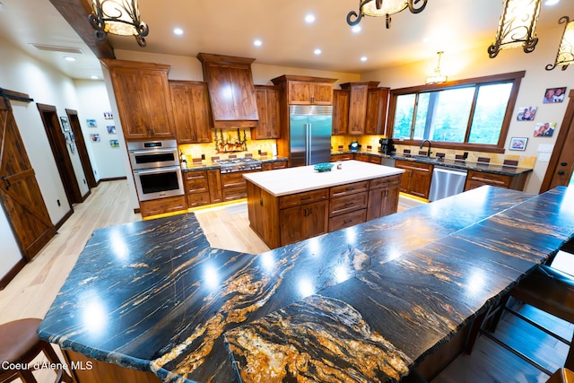 9057 W Benton Way, Coeur Dalene, ID 83814 - kitchen featuring stainless steel appliances, premium range hood, a center island, brown cabinets, and a chandelier