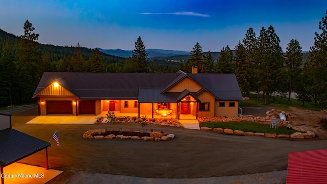 9057 W Benton Way, Coeur Dalene, ID 83814 - view of front of house with driveway, metal roof, a forest view, a mountain view, and an attached garage