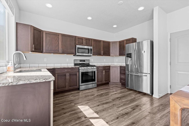 1482 N Skykomish Dr, Post Falls, ID 83854 - kitchen with stainless steel appliances, a sink, dark wood finished floors, light stone countertops, and dark brown cabinetry