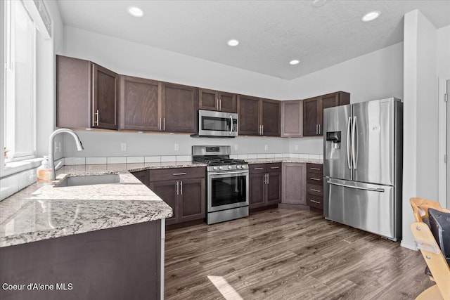 1482 N Skykomish Dr, Post Falls, ID 83854 - kitchen featuring appliances with stainless steel finishes, a sink, dark wood-style floors, dark brown cabinetry, and light stone counters