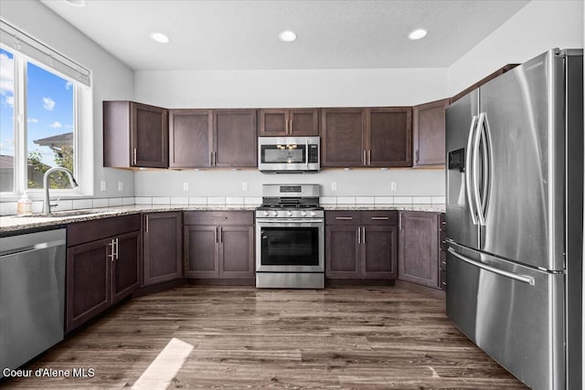 1482 N Skykomish Dr, Post Falls, ID 83854 - kitchen with stainless steel appliances, a sink, dark wood-style floors, light stone counters, and dark brown cabinets