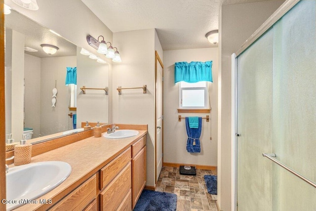 8558 N Boysenberry Loop, Hayden, ID 83835 - bathroom featuring stone finish flooring, double vanity, a shower stall, baseboards, and toilet