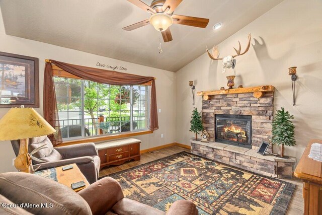 8558 N Boysenberry Loop, Hayden, ID 83835 - living room with wood finished floors, lofted ceiling, a fireplace, ceiling fan, and baseboards