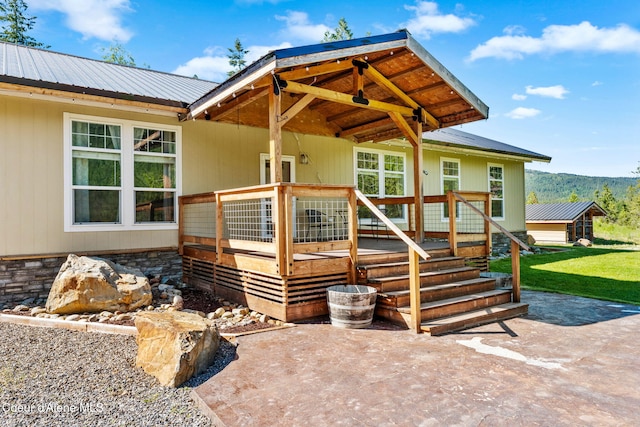 1446 Sagle Creek Rd, Sagle, ID 83860 - view of exterior entry featuring metal roof, a patio area, a lawn, and a wooden deck