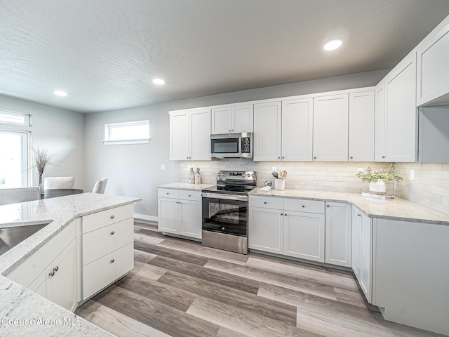 13668 N Apex Way, Hayden, ID 83835 - kitchen with appliances with stainless steel finishes, light stone counters, decorative backsplash, white cabinetry, and recessed lighting