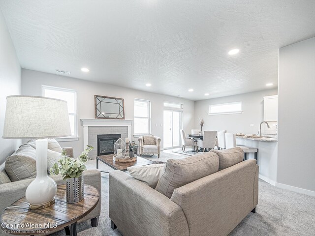 13668 N Apex Way, Hayden, ID 83835 - living room with a glass covered fireplace, recessed lighting, baseboards, light carpet, and a textured ceiling