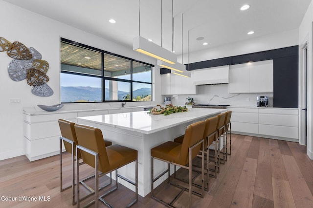175 N Holidays Hills Dr, Liberty Lake, WA 99019 - kitchen featuring modern cabinets, a center island, exhaust hood, a kitchen breakfast bar, and white cabinets