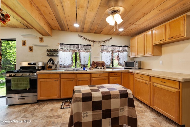910 Otts Rd, Sagle, ID 83860 - kitchen featuring stainless steel gas range oven, wood ceiling with exposed beams, tile counters, a sink, and stone finish floors