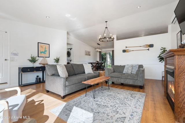 9298 N Clarkview Pl, Hayden, ID 83835 - living room with stacked washer and clothes dryer, a chandelier, wood finished floors, a glass covered fireplace, and lofted ceiling