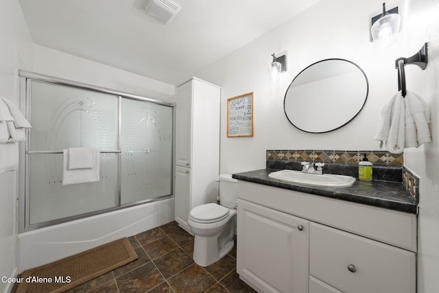 9298 N Clarkview Pl, Hayden, ID 83835 - bathroom with vanity, enclosed tub / shower combo, toilet, stone finish flooring, and tasteful backsplash