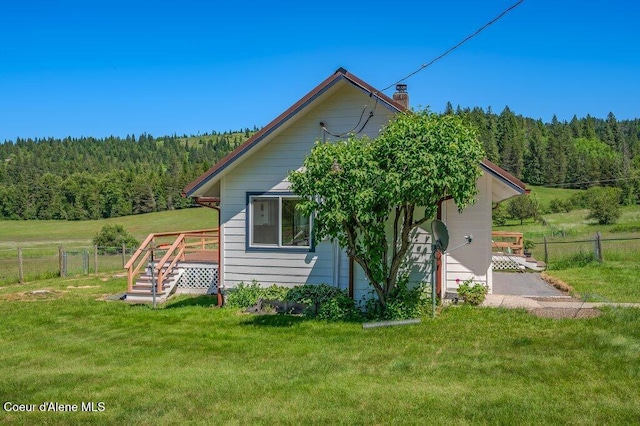 25024 N Derting Rd, Hayden, ID 83835 - rear view of house with a wooded view, a chimney, and a deck