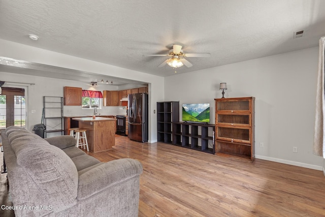 6687 W Flagstaff St, Rathdrum, ID 83858 - living area with light wood-style floors, a ceiling fan, baseboards, and a textured ceiling