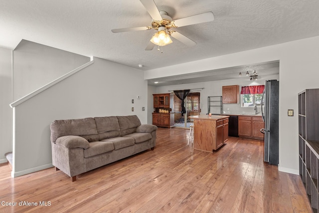 6687 W Flagstaff St, Rathdrum, ID 83858 - living room featuring light wood finished floors, a textured ceiling, a ceiling fan, and baseboards