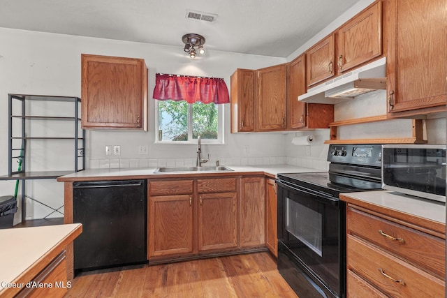 6687 W Flagstaff St, Rathdrum, ID 83858 - kitchen featuring black appliances, under cabinet range hood, a sink, light wood-style floors, and light countertops