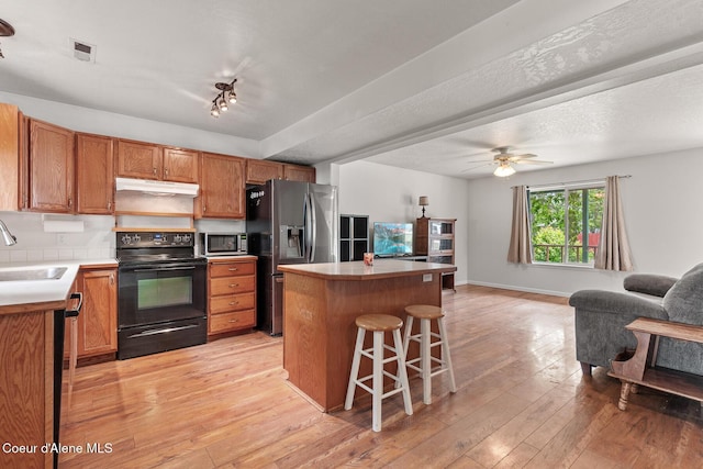 6687 W Flagstaff St, Rathdrum, ID 83858 - kitchen featuring stainless steel appliances, under cabinet range hood, open floor plan, a breakfast bar area, and a kitchen island