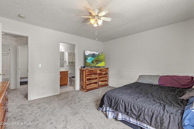 6687 W Flagstaff St, Rathdrum, ID 83858 - bedroom with light carpet, a wainscoted wall, connected bathroom, a textured ceiling, and a ceiling fan