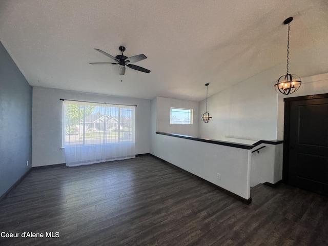 8309 N Vantage Dr, Hayden, ID 83835 - unfurnished living room featuring dark wood-style flooring, a chandelier, a ceiling fan, a textured ceiling, and baseboards