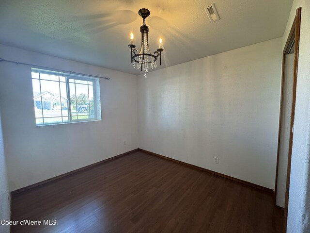 8309 N Vantage Dr, Hayden, ID 83835 - unfurnished room featuring a chandelier, wood finished floors, baseboards, and a textured ceiling